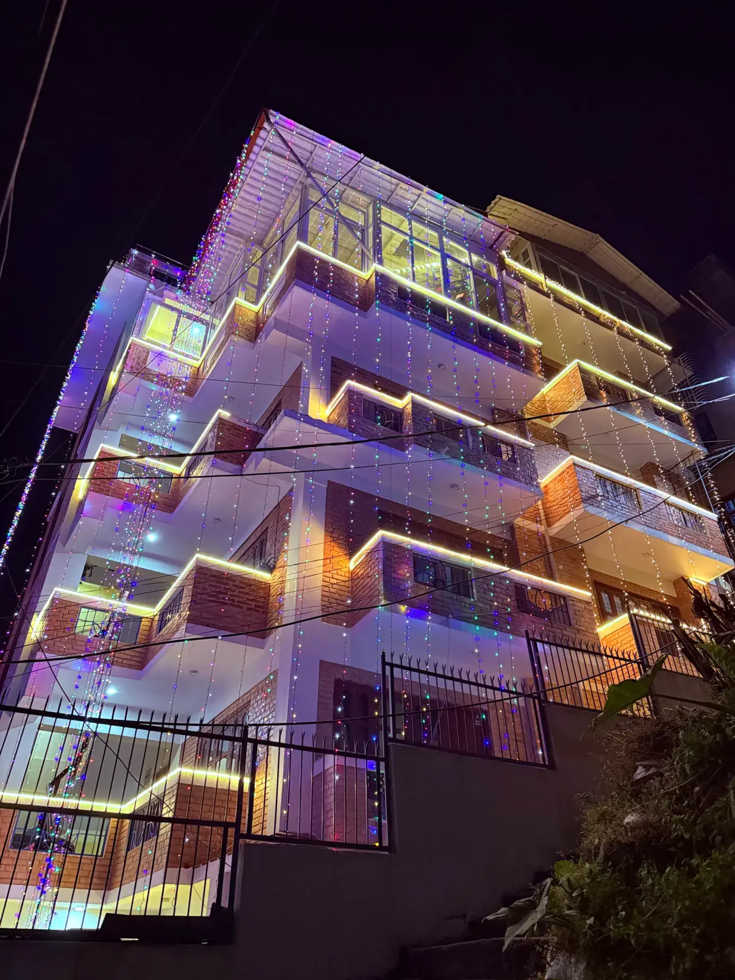 The Sacred Trails homestay building lit with festival lights at night