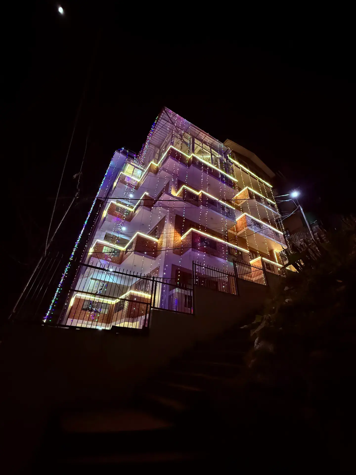 Side view of the illuminated homestay building on the Budhanilkantha hillside