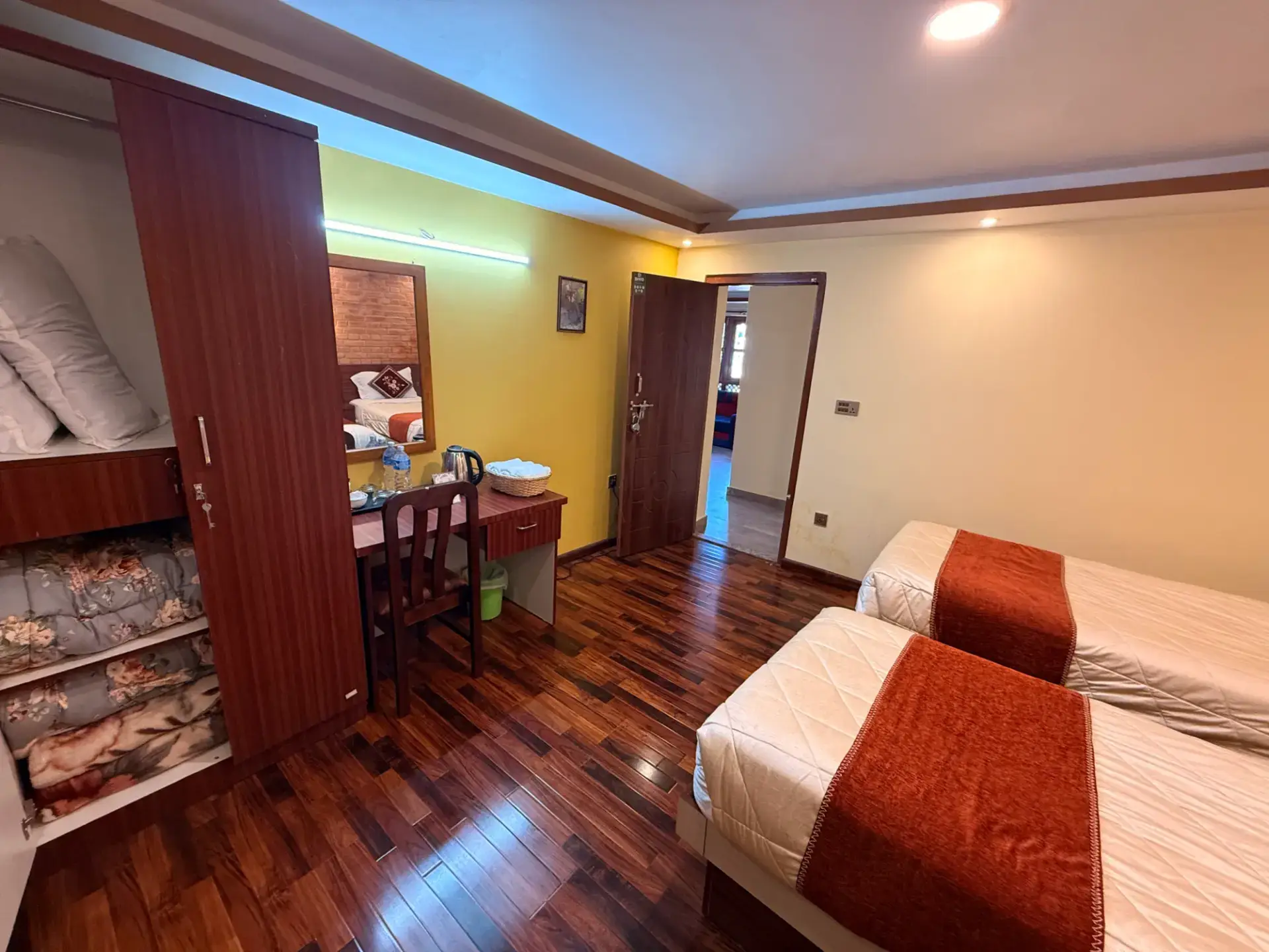 Twin room with wardrobe, desk and two single beds made with orange runners
