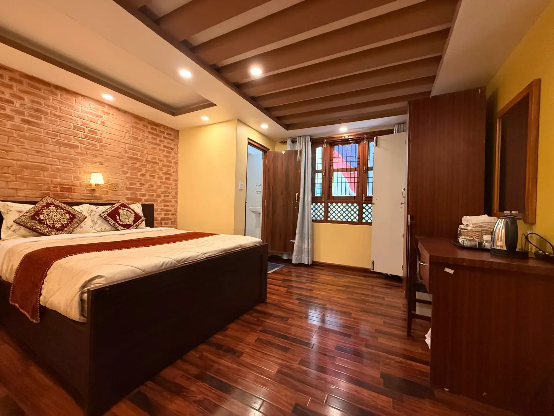 King bed beside a traditional brick wall and wooden beams